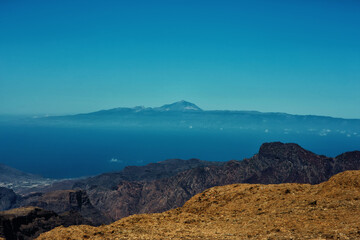 Edge of mountains on the island Gran Canaria with sky, neighboring island Tenerife  and volcano Tejde on the background 