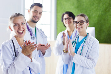 Fototapeta premium Happy medical team comprising male and female doctors smiling broadly and giving a thumbs up of success and hope