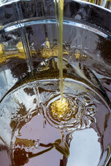 Fresh liquid honey is poured into a metal container