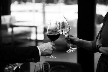 hands of man and woman with glasses of wine, black and white photo