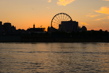 Montreal Grand Ferris Wheel in Old Port at sunset. Reflections of sun rays on Saint Laurent river...