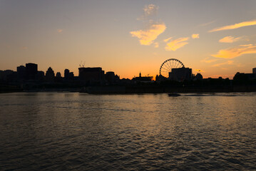 Montreal Downtown skyline at sunset. Reflections of sun rays on Saint Laurent river with a background of cloudy blue sky