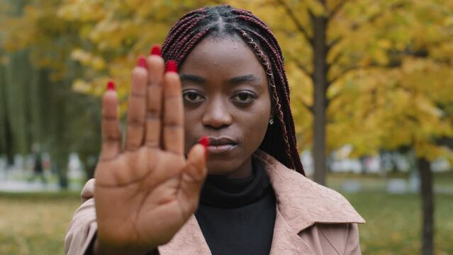 Close-up young serious focused angry african american woman holding palm in front showing stop gesture showing prohibition sign forbidden protect personal boundaries against discrimination violence