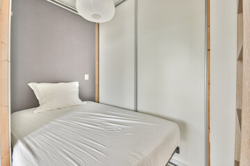 Comfortable bed with ornamental blanket placed near glass door and wardrobe with mirror in light bedroom