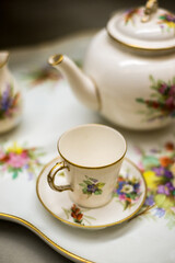 Close up of a classic, vintage cup and saucer placed along with tea pot. Antique, porcelain tea set with vintage design.