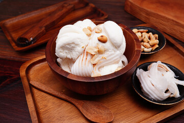Coconut milk ice cream cup, round balls and young coconut Garnish with cooked roasted peanuts. (spot focus)