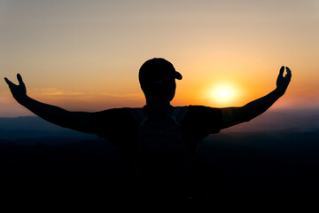 Sunset with a silhouette of a young man in an attitude of gratitude to the sun