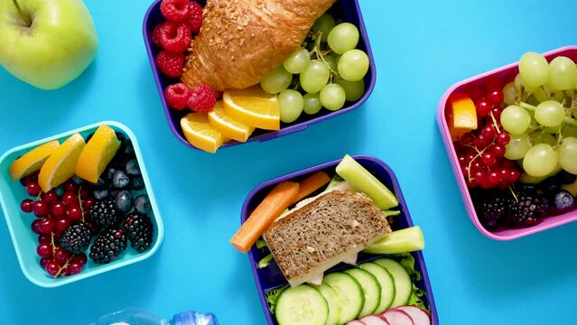 Shot of school lunchboxes with various healthy nutritious meals on blue background