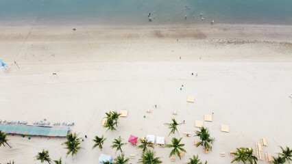 White sandy beach park with folding chairs, picnic tables, wedding decorations and palm trees near Tuan Chau Island, Ha Long City, Quang Ninh