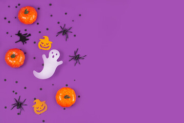 Halloween decorations pumpkins spiders with black confetti on violet background.