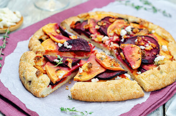 Sweet potato beets galette with goat cheese and thyme on a wood background