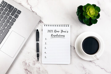 Note pad with text 2023 New Year resolutions on top of office desk © cn0ra