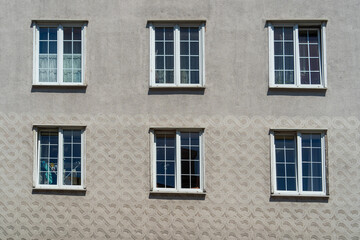 Fototapeta na wymiar Six windows with white wooden frames on a wall with gray 3D stucco on a sunny day in the historic center of Gdansk, Poland