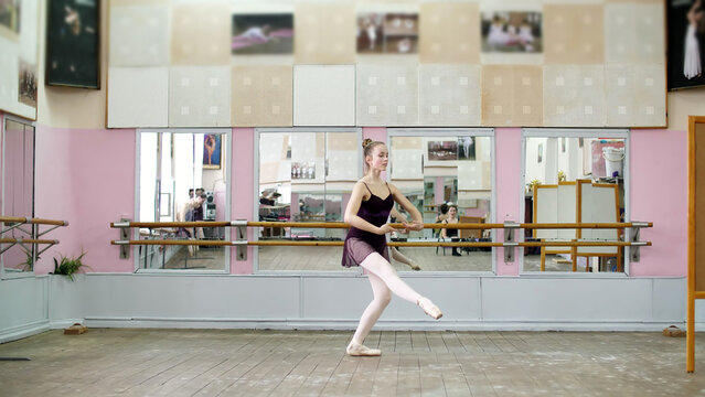 in dancing hall, Young ballerina in black leotard performs pas courru , pointe , She is moving through the ballet class elegantly,. High quality photo