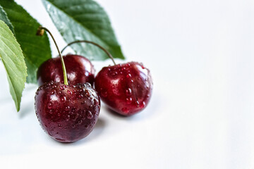 Juicy ripe cherry on a white background, close-up. Red cherry berries on a light background with green leaves. Selective focus. The concept of healthy eating.