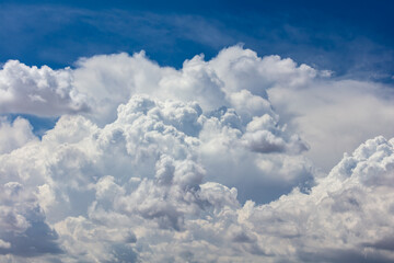 Fototapeta na wymiar Closeup of Billowy cumulus clouds. Wispy clouds, deep blue sky in background. 