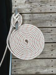 Nautical Style Rope Wound Up into a Spiral Circle on a Boat Dock. Looking down over a pier between...