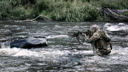 Mercenary military sniper during a sabotage mission behind enemy lines. He stands waist-deep in the river and aims at the enemy.