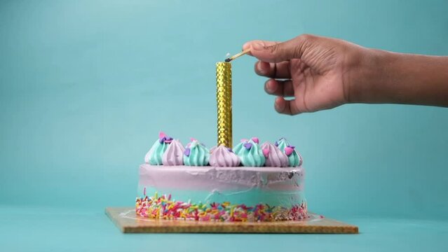 slow motion of burning candle on a birthday cake on light purple background 