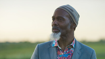 Portrait of stylish senior black male with white goatee staring into the distance as he stands in...
