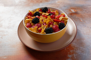 Corn flakes with berries in a bowl, served with milk.
