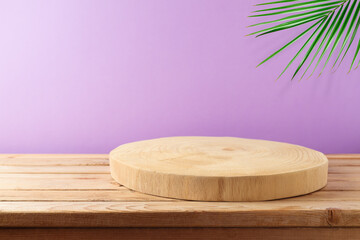 Empty wooden log on table over purple wall and palm leaf background. Kitchen or home interior for mock up design