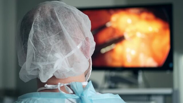 The operating surgeon looks at the big screen in the operating room during the operation. The surgeon moves a small camera to see the progress of the operation. Modern technologies in medicine