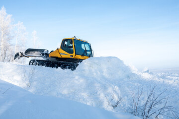 Fototapeta na wymiar yellow tractor for leveling snow on the ski slope