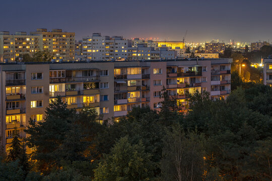 Wielorodzinne osiedle mieszkaniowe nocą. Wysokie bloki mieszkalne, światła w oknach.