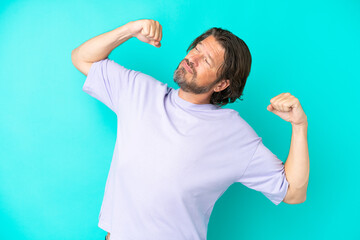 Senior dutch man isolated on blue background doing strong gesture