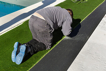 Obrero instalando césped artificial en un jardín.