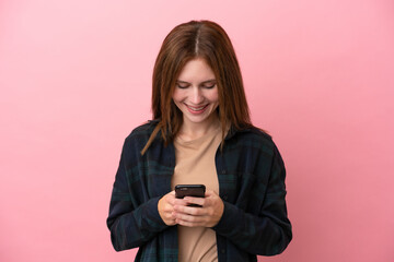 Naklejka premium Young English woman isolated on pink background sending a message with the mobile