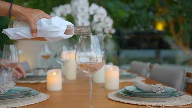 Wide shot of a waiter pouring white wine into the wine glass, waiter serve a diner table