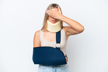 Woman with broken arm and wearing a sling isolated on white background covering eyes by hands. Do...