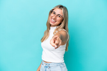Young caucasian woman isolated on blue background pointing front with happy expression