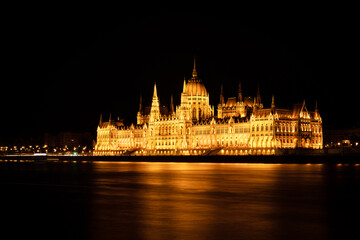 Fototapeta na wymiar Hungarian Parliament Building or Országház in front of the Danube river at night. Beautiful night landscape with an illuminated monument. Summer landscape scene from the city of Budapest, Hungary