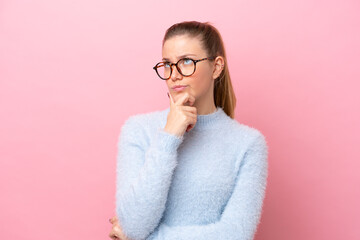Young caucasian woman isolated on pink background having doubts