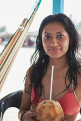 young latin woman with dark skin drinking coco water