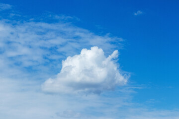 A big white fluffy cloud of a strange shape in the blue sky