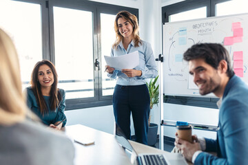 Elegant businesswoman having a meeting front of white blackboard and explain a project to her...