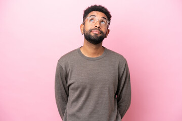 Young Brazilian man isolated on pink background and looking up
