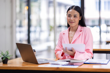 Business Asian woman working in the workplace with documents on her desk, doing planning analyzing the financial report, business plan investment, finance analysis concept	