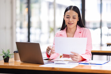 Business Asian woman working in the workplace with documents on her desk, doing planning analyzing the financial report, business plan investment, finance analysis concept	