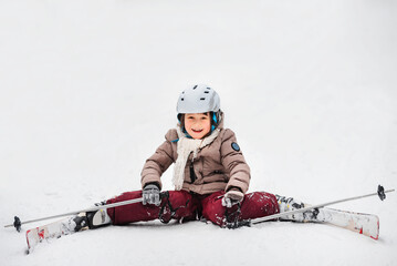 Fototapeta na wymiar Little happy girl is learning to ski. Ski equipment, winter clothes. Active sports entertainment during the winter holidays.