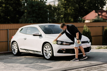 Man is wiping the car with a microfiber cloth. Contactless self-service car wash. Personal car care...