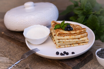 pancakes are placed in a triangle with blueberries on a white plate laid on a wooden background