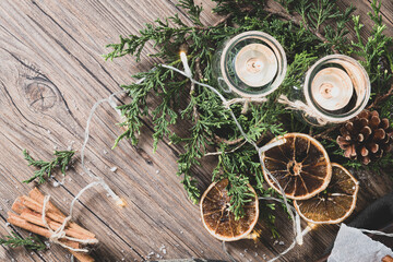 Background for christmas with burning candles and natural decoration on rustic wooden board. Background with pine branches and space for your text.
