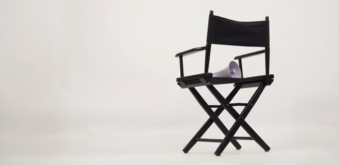 Back of Black director chair and yellow megaphone put on chair on white background.