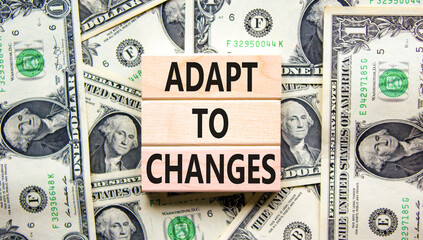 Adapt to changes symbol. Concept words Adapt to changes on wooden blocks on dollar bills. Beautiful background from dollar bills. Business and Adapt to changes quote concept. Copy space.