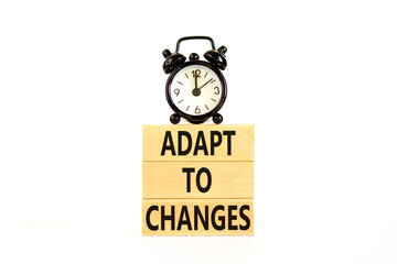 Adapt to changes symbol. Concept words Adapt to changes on wooden blocks. Black alarm clock. Beautiful white table white background. Business and Adapt to changes quote concept. Copy space.